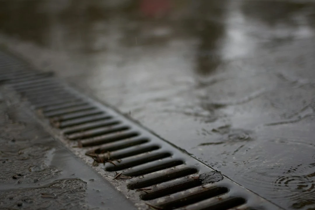 Caniveau de garage bouché avec eau stagnante devant une évacuation au sol