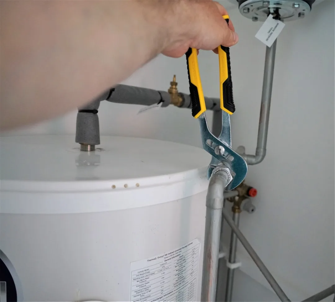 Plombier intervenant sur une installation, illustration d’un chauffe-eau qui fuit par le bas