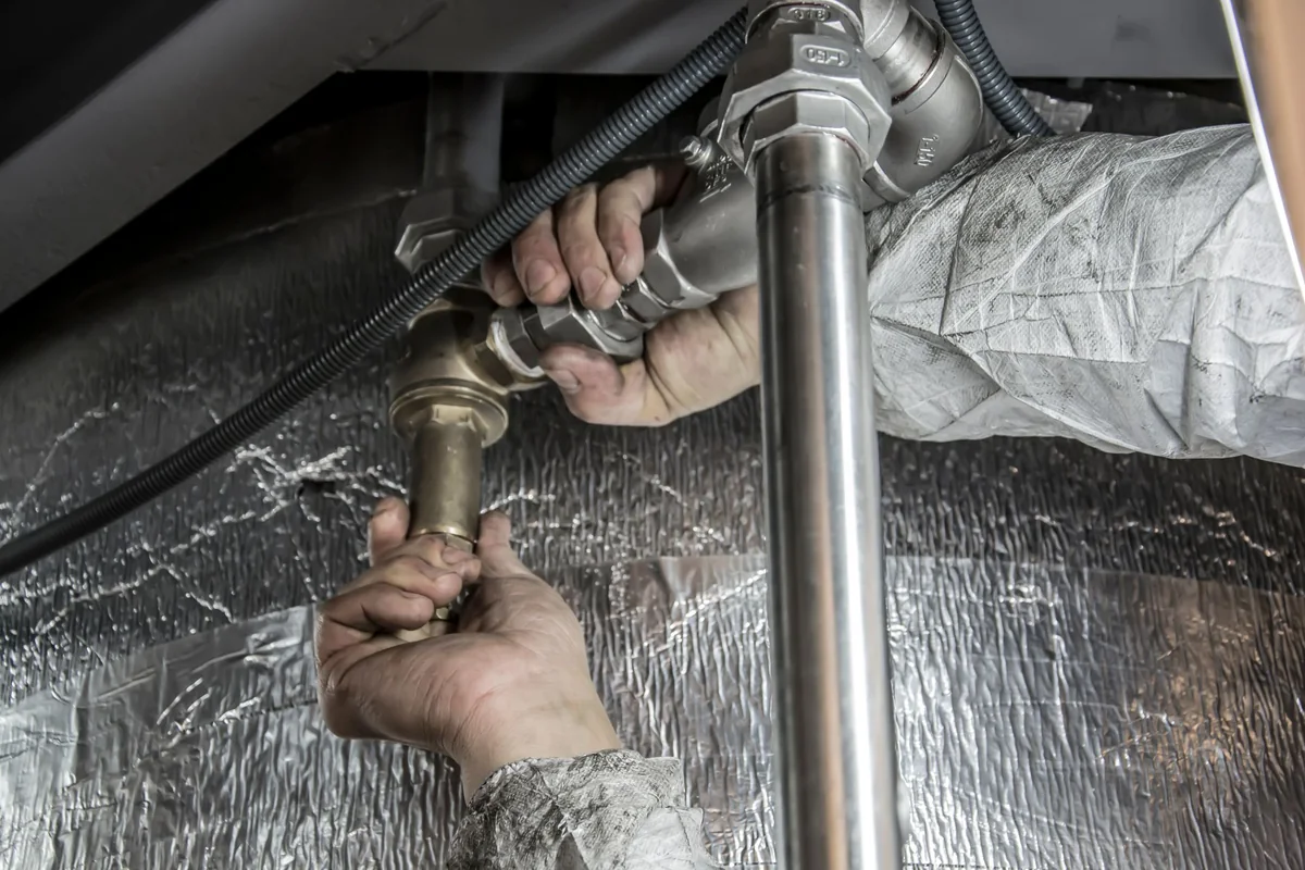Technicien préparant la vidange d un chauffe-eau électrique avec contrôle du groupe de sécurité